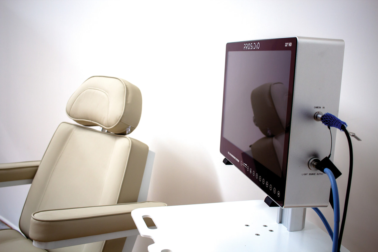 Prosidio endoscopy display beside an examination chair with two cables connected at the side panel