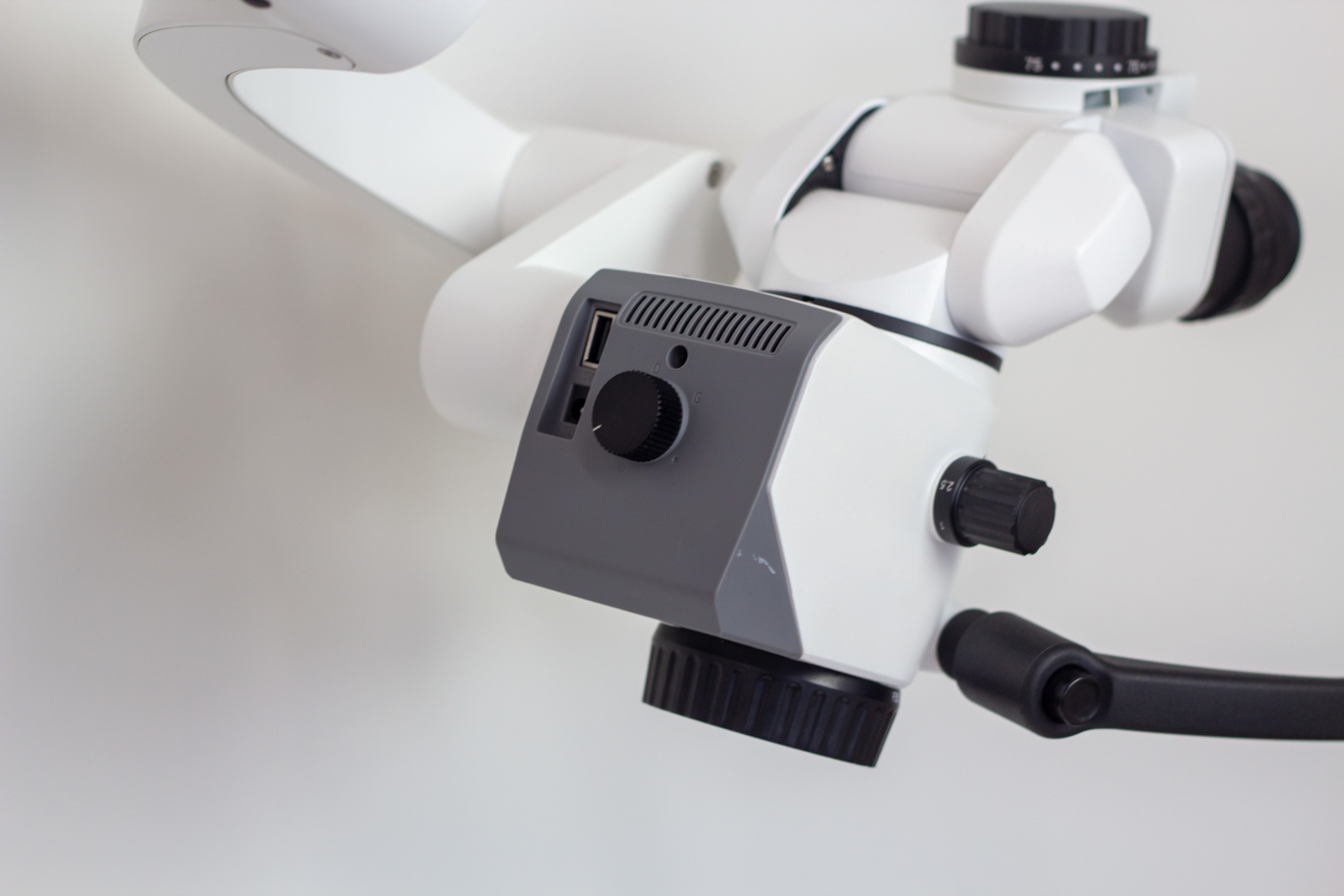 Close-up of a white surgical microscope body and binocular eyepieces